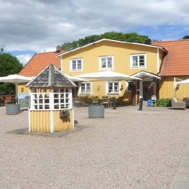 Gul gårdsbyggnad med uteplats och entré