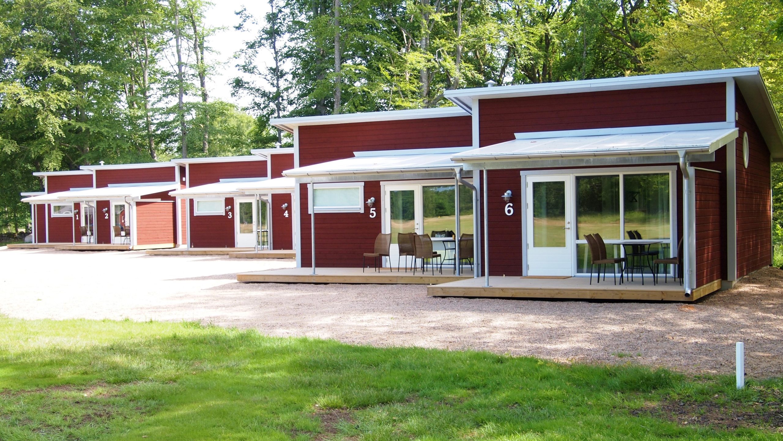 Röda stugor vid Wittsjö Golfklubb i grön skogsmiljö